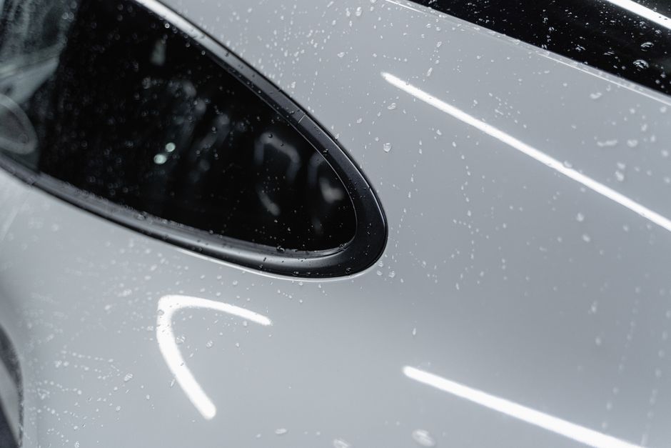 Clean white car covered in water droplets, shining after a wash.