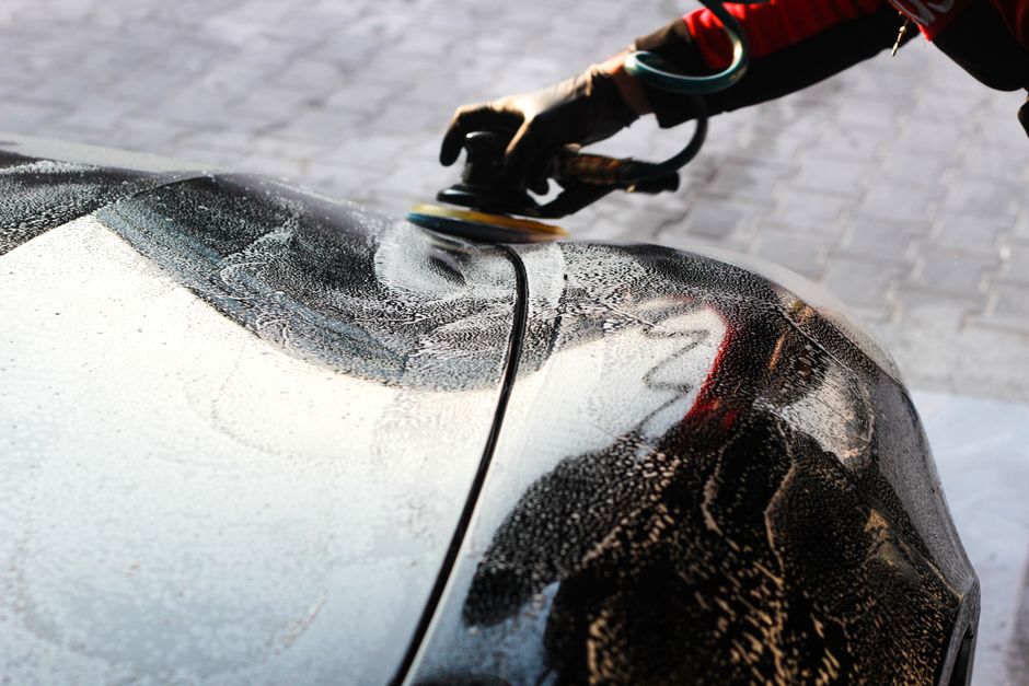 Detailer hand-polishing a car's bodywork with a cloth.